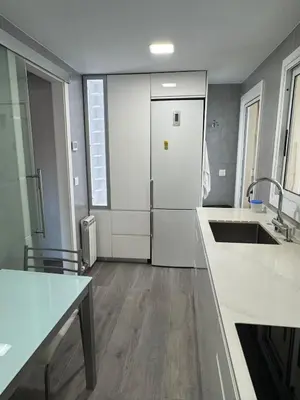 a kitchen with white counters and a sink and a refrigerator at Atico espectacular Cunit in Cunit