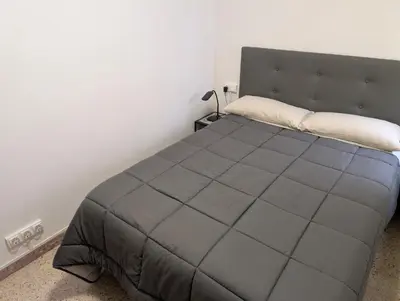 a bedroom with a large bed with a gray blanket at Apartamento Barcelona in Hospitalet de Llobregat