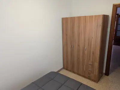 a bedroom with a wooden cabinet next to a bed at Apartamento Barcelona in Hospitalet de Llobregat