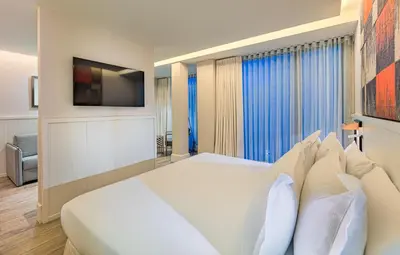 a bedroom with a large white bed and a tv at H10 Cubik 4* Sup in Barcelona