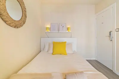 a white bedroom with a yellow pillow on a bed at Atlantida House Self Check-in in Hospitalet de Llobregat