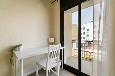 a white desk and chair in a room with a window at Atlantida House Self Check-in in Hospitalet de Llobregat