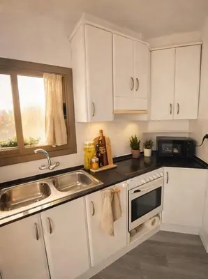 a kitchen with white cabinets and a sink and a window at Atlantida House Self Check-in in Hospitalet de Llobregat