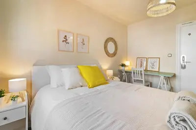 a bedroom with a large white bed with yellow pillows at Atlantida House Self Check-in in Hospitalet de Llobregat