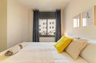 a bedroom with a white bed with yellow pillows at Atlantida House Self Check-in in Hospitalet de Llobregat