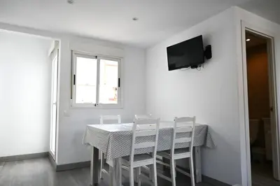 a dining room table with chairs and a television on a wall at Homenfun Barcelona Camp Nou in Hospitalet de Llobregat