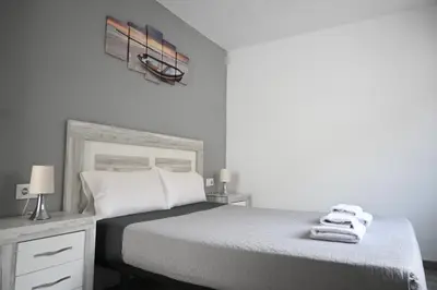 a white bedroom with a bed with towels on it at Homenfun Barcelona Camp Nou in Hospitalet de Llobregat
