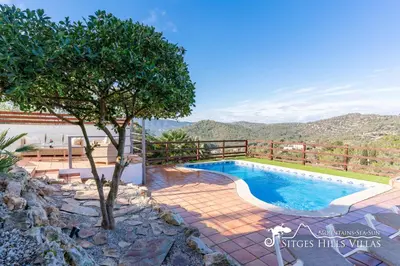 a bedroom with a white bed and a night stand at Sunny Villa Moments near Sitges in Olivella
