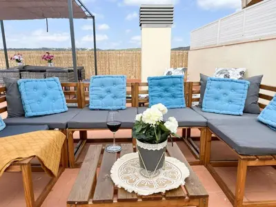 a patio with blue chairs and a table with a glass of wine at Apartment Sunset in Cunit