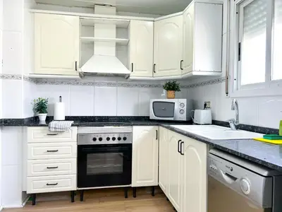 a white kitchen with white cabinets and a microwave at Apartment Sunset in Cunit