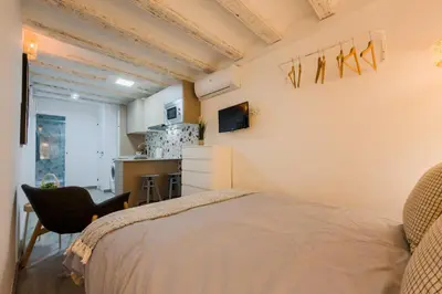 a bedroom with a bed and a chair and a kitchen at Acogedor y céntrico Estudio 1 in Barcelona