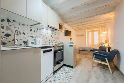 a kitchen with white cabinets and a blue chair at Acogedor y céntrico Estudio 2 in Barcelona