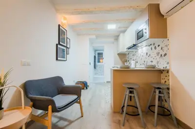 a living room with a chair and a kitchen at Acogedor y céntrico Estudio 2 in Barcelona