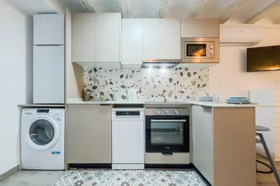 a kitchen with white cabinets and a washer and dryer at Acogedor y céntrico Estudio 2 in Barcelona