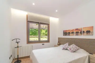 a white bedroom with a large bed and a window at Casa con piscina salina a 5 minutos de Sitges in Canyelles