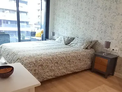a bedroom with a bed and a table and a window at Rooftop pool near the beach and Barcelona in Masnou