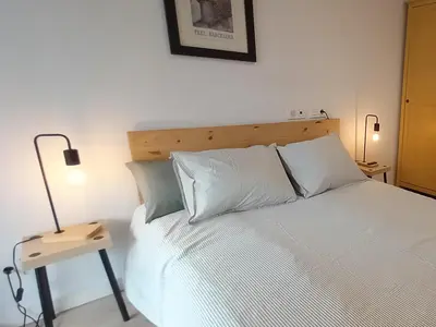 a bedroom with a white bed with a nightstand next to it at Rooftop pool near the beach and Barcelona in Masnou