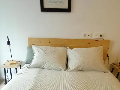 a bed with white sheets and a wooden headboard at Rooftop pool near the beach and Barcelona in Masnou