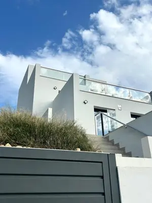 a white house with glass walls and stairs at Les Flors de Cunit Villa Edelweiss in Cunit