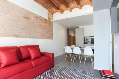 a red couch in a living room with a brick wall at Aparteasy - Deluxe Family Apartments with Pool in Barcelona