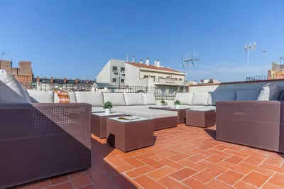 a patio with couches and tables on a roof at Aparteasy - Deluxe Family Apartments with Pool in Barcelona