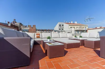 a rooftop patio with couches and tables on a roof at Aparteasy - Deluxe Family Apartments with Pool in Barcelona