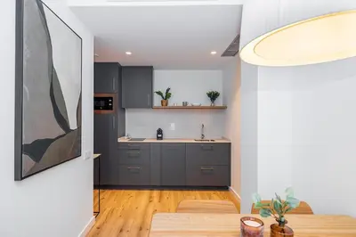 a kitchen with gray cabinets and a kitchen table at Brabo Apartments in Hospitalet de Llobregat
