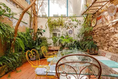 a patio with a glass table and chairs in a greenhouse at Vintage home in Barcelona