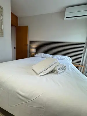 a white bed with two towels on top of it at Ocean View Sunny Beach Apartment Castelldefels in Castelldefels