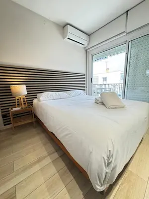 a bedroom with a large white bed and a chair at Ocean View Sunny Beach Apartment Castelldefels in Castelldefels