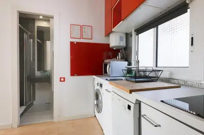 a kitchen with red cabinets and a washer and dryer at ApartEasy - Lovely Atic in Barcelona in Barcelona