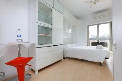 a white bedroom with a bed and a red chair at ApartEasy - Lovely Atic in Barcelona in Barcelona