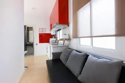 a living room with a couch and a kitchen at ApartEasy - Lovely Atic in Barcelona in Barcelona