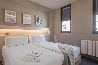 a bedroom with a white bed with a book on it at BCN MONTJUÏC Apartments in Barcelona