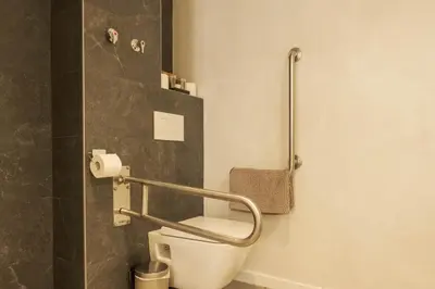 a bathroom with a toilet with a rail on the wall at GuestReady - ARIQUS Apartments in Barcelona