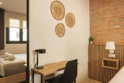a bedroom with a desk and a bed and a brick wall at GuestReady - ARIQUS Apartments in Barcelona