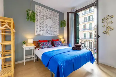 a bedroom with a bed with blue sheets and a window at Studio Premium en Sants a 15' Bcn Centro y Fira Bcn in Barcelona