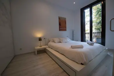 a white bedroom with a large bed with a window at Roger De Lluria Design Apartment in Barcelona