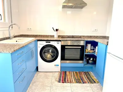 a blue kitchen with a washing machine and a sink at Camins de Montserrat in El Bruc