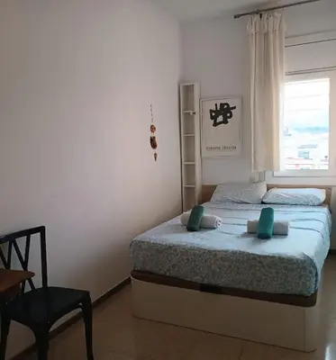 a bedroom with a bed and a chair and a window at Vivalidays Andrea - Pineda de Mar in Pineda de Mar