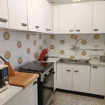 a kitchen with white cabinets and a stove and sink at Vivalidays Andrea - Pineda de Mar in Pineda de Mar