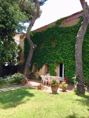 a building covered in green ivy with a table in the yard at Casa de pueblo con jardín in Premiá de Mar