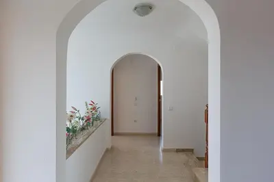 an archway leading to a hallway with white walls and flowers at Fantástica casa en alquiler con piscina en Vilanova i la Geltrú in Vilanova i la Geltrú