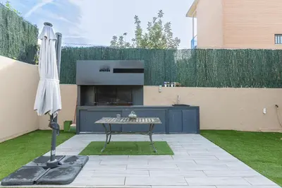 a patio with a table and an umbrella in a yard at Fantástica casa en alquiler con piscina en Vilanova i la Geltrú in Vilanova i la Geltrú
