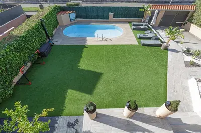 a backyard with a swimming pool and green grass at Fantástica casa en alquiler con piscina en Vilanova i la Geltrú in Vilanova i la Geltrú