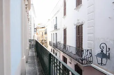 an alley with white buildings and a balcony at Ca La Manso in Sitges