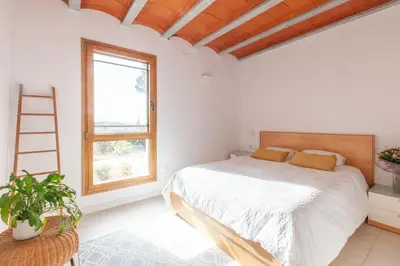 a white bedroom with a bed and a window at Aldana accommodation in the middle of nature in Molins de Rei