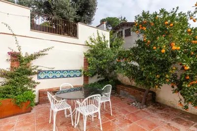 a patio with a table and chairs and an orange tree at Aldana accommodation in the middle of nature in Molins de Rei