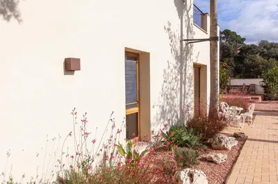 a white house with a garden with flowers at Aldana accommodation in the middle of nature in Molins de Rei