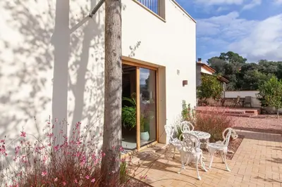 a white house with white chairs and a table at Aldana accommodation in the middle of nature in Molins de Rei
